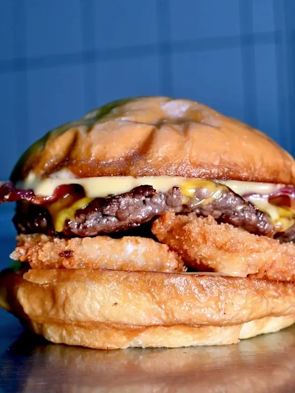 Hamburguesa con tocino, queso y aros de cebolla sobre fondo azul