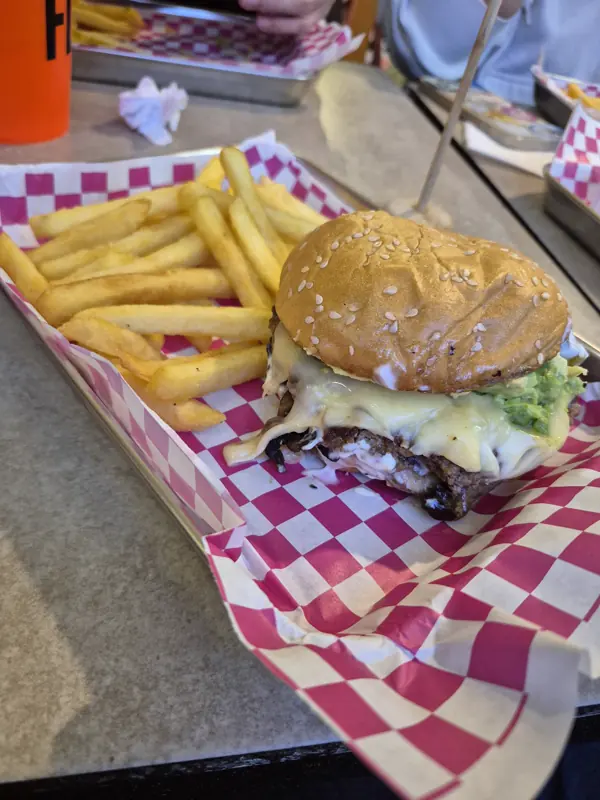 Hamburguesa con papas fritas en bandeja con papel a cuadros