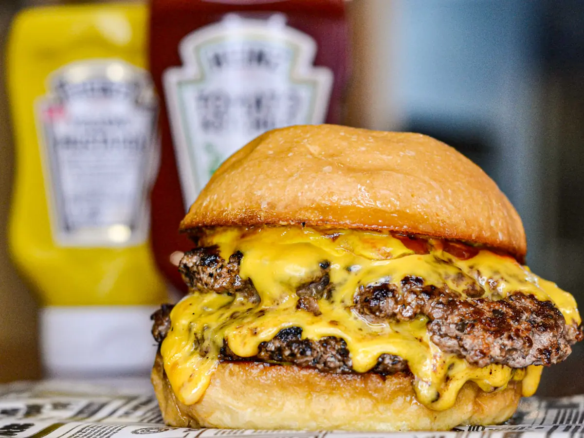 Hamburguesa doble con queso americano fundido, con ketchup y mostaza Heinz atrás