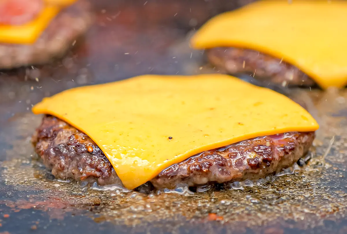 Carnes con queso americano fundiéndose en la plancha